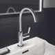 Waschtischarmatur von Ideal Standard mit schwenkbarem Auslauf und einem Hebel zum Regulieren der Wasserzufuhr, montiert auf einer weißen Waschbeckenoberfläche.